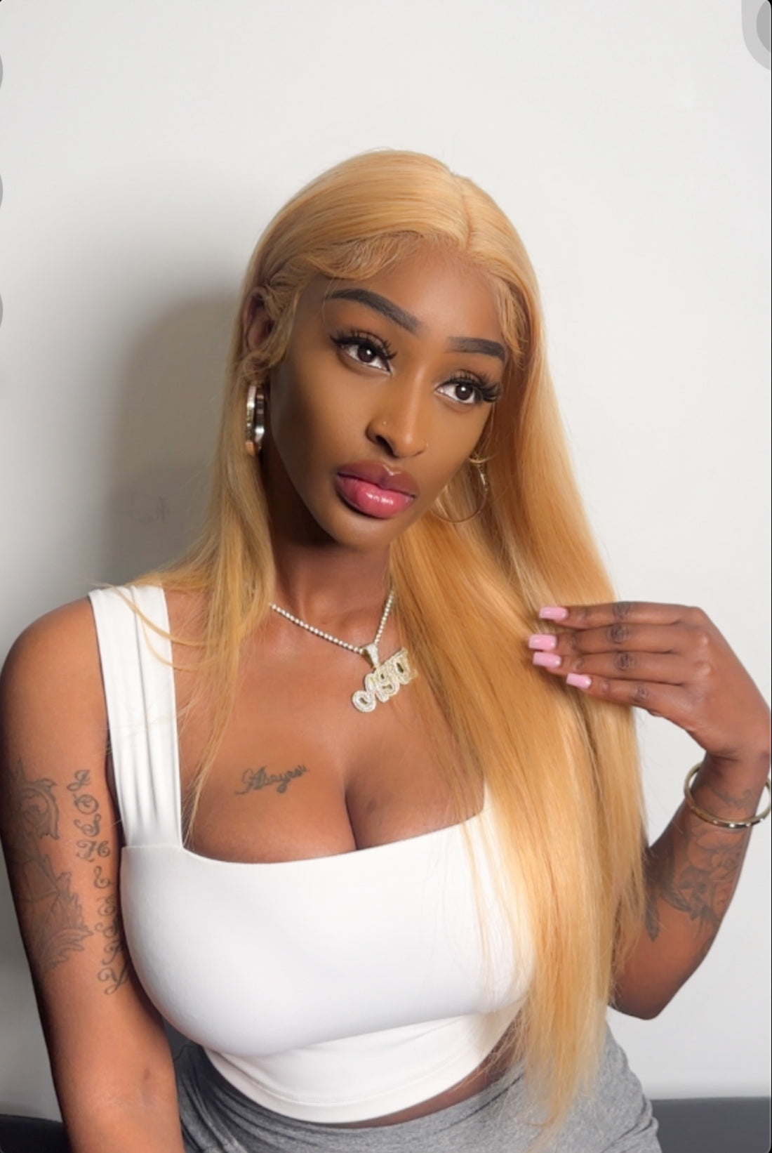 A person wearing a straight honey blonde lace wig with a pre-plucked hairline.