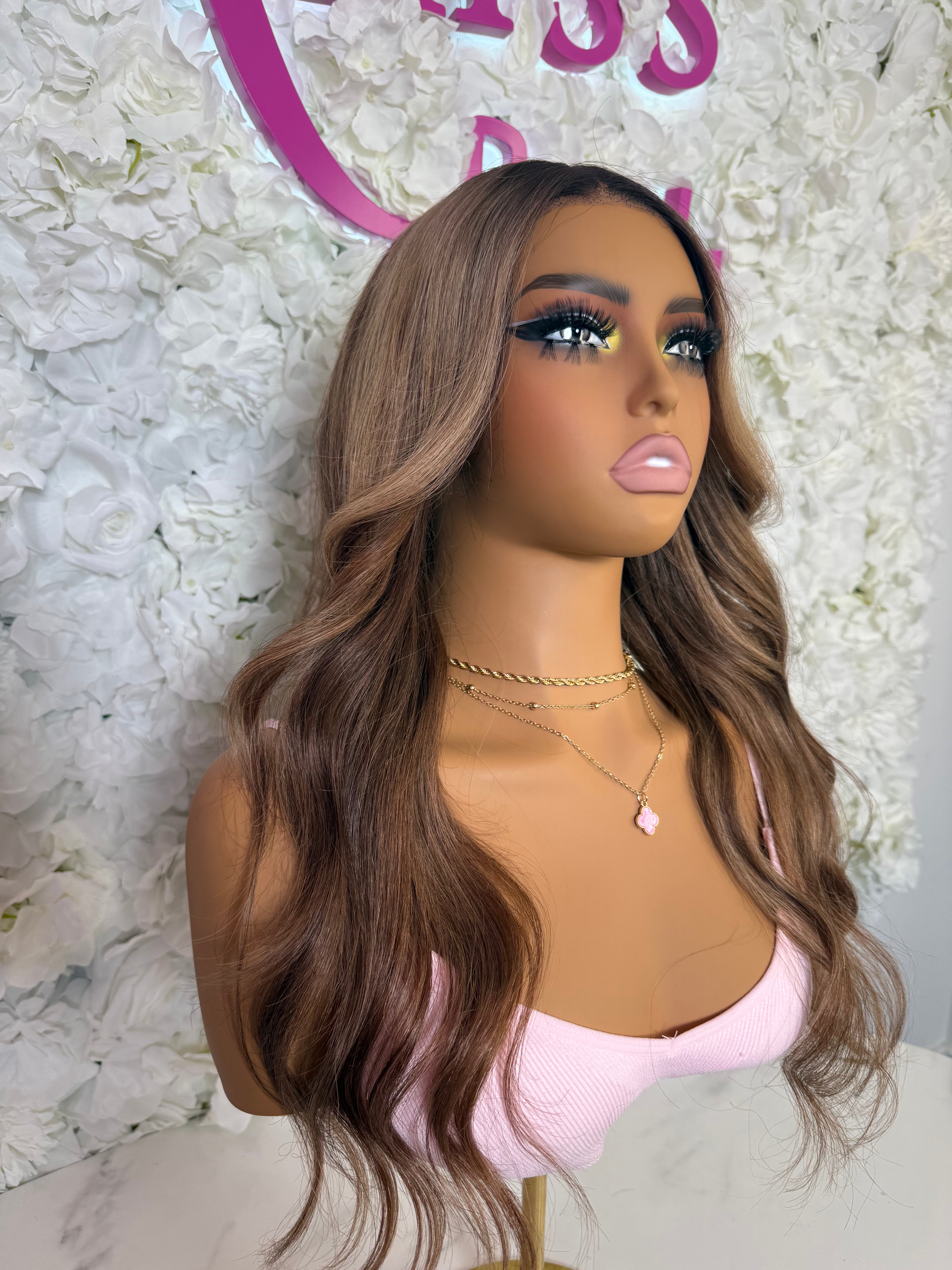 Mannequin head with long brown wig against a floral background