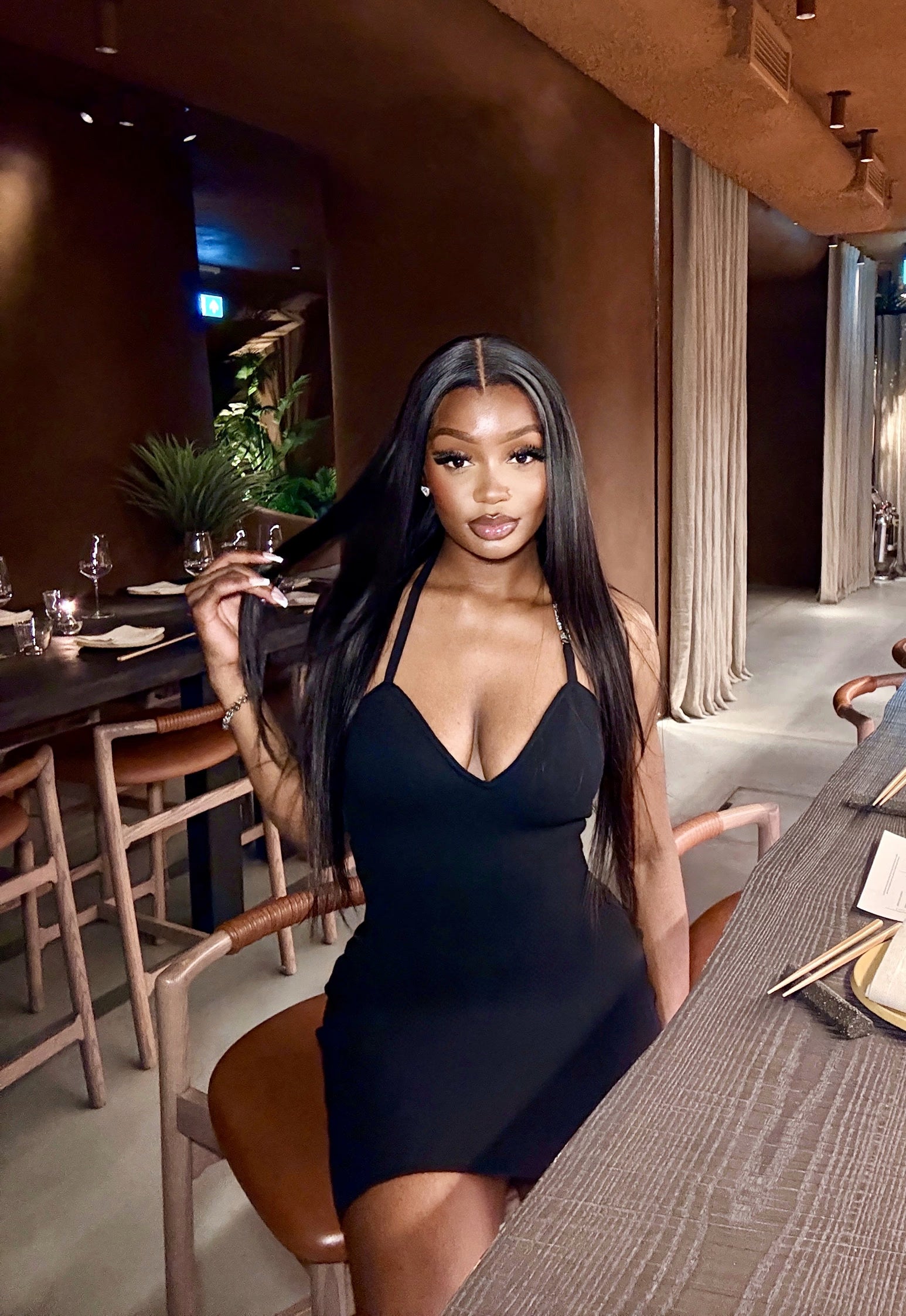 Woman in a black dress sitting at a table in a restaurant setting