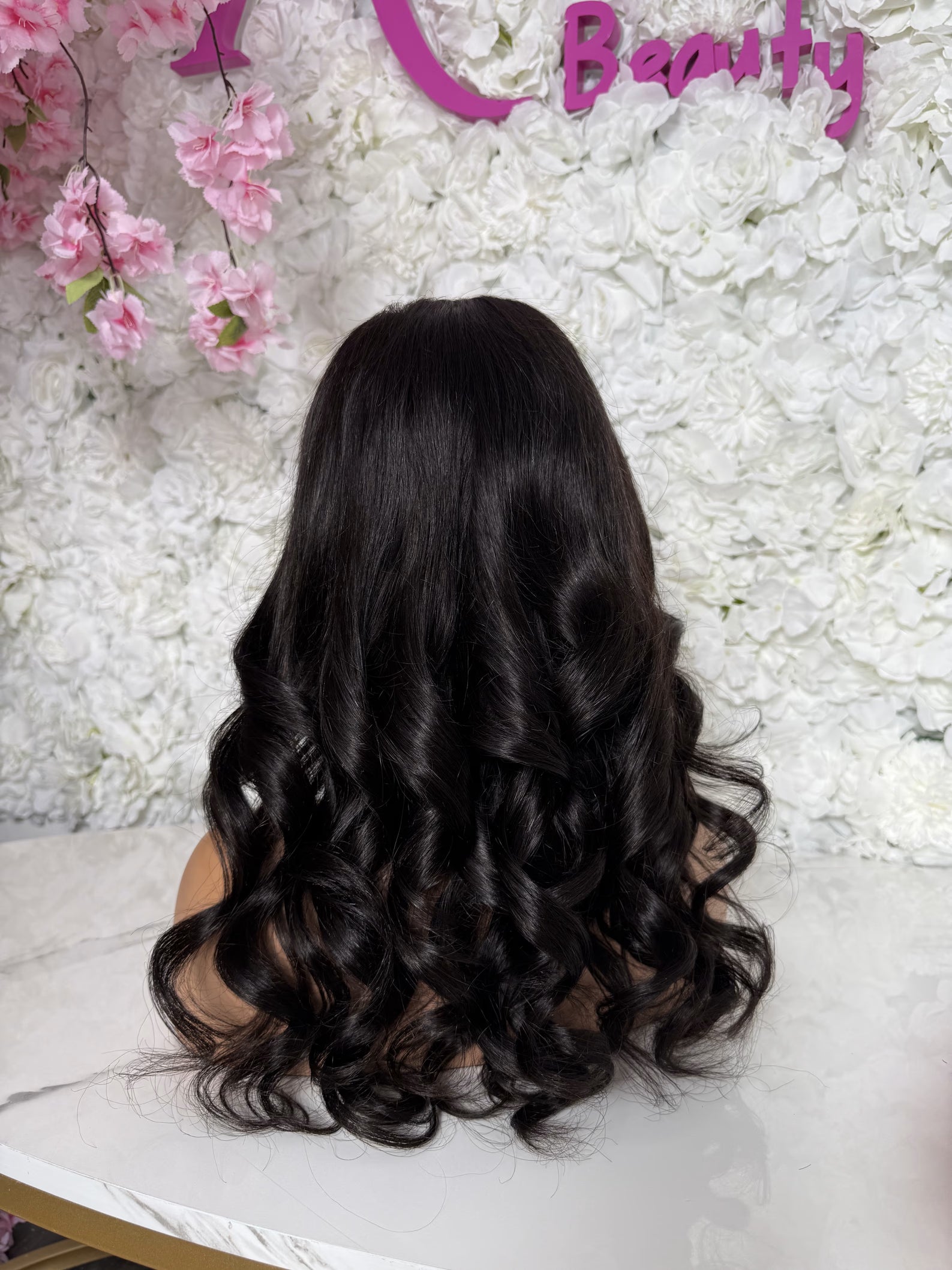 Black wig on a mannequin head with a floral and &