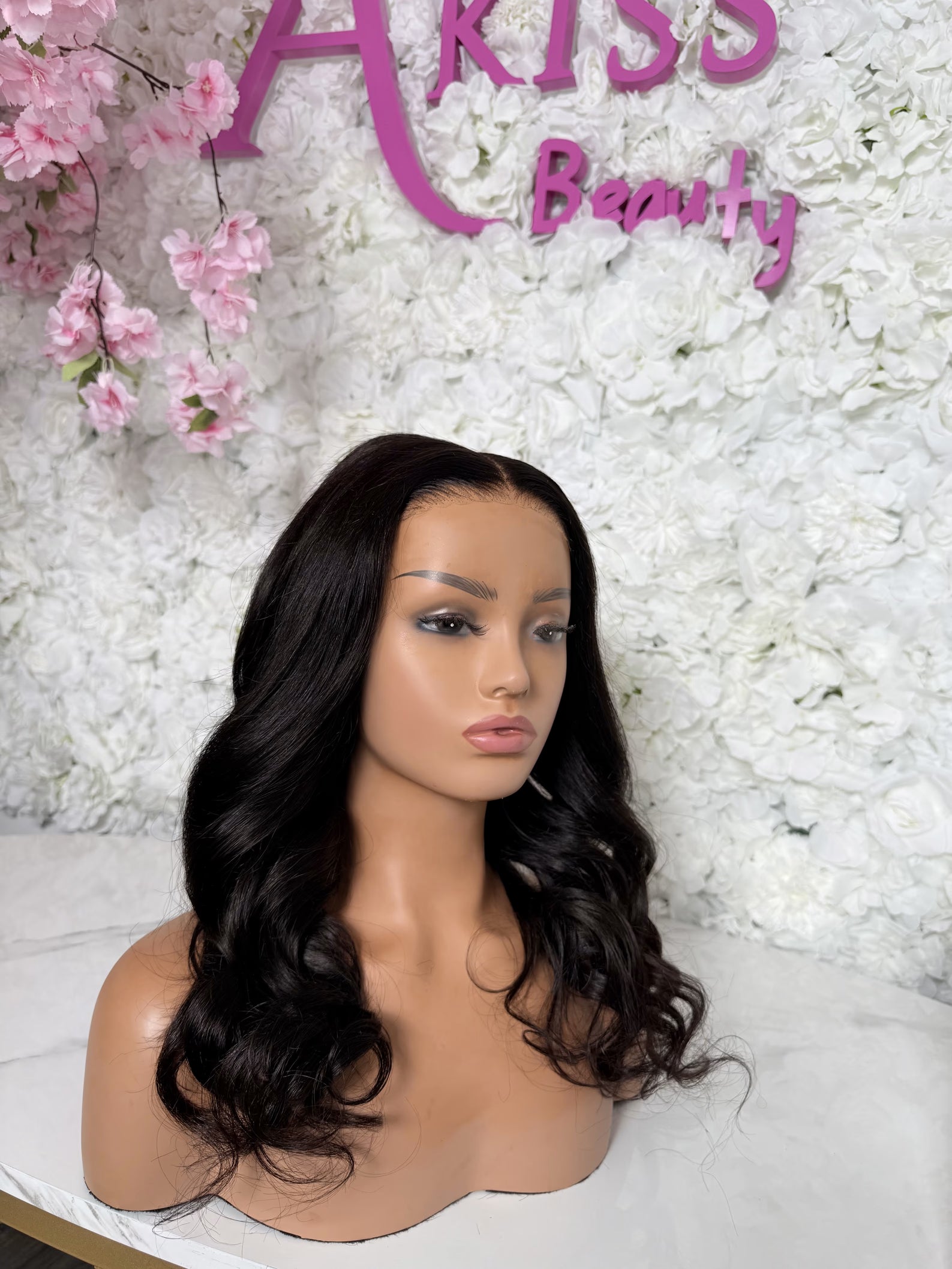 Mannequin head with a black wig against a floral and &