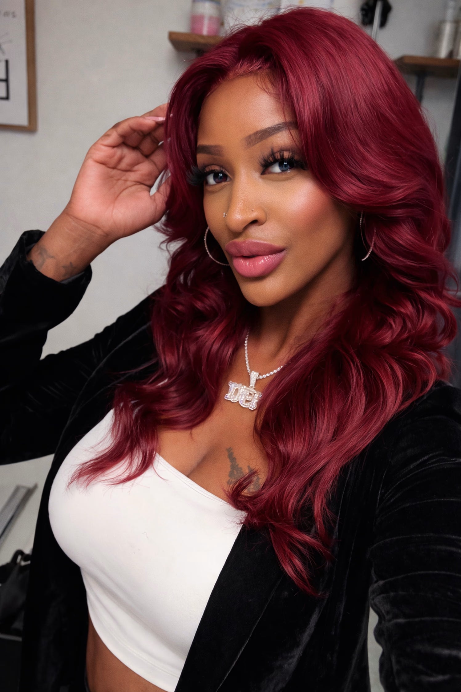 Woman with vibrant red hair styled in loose waves, wearing a black jacket and white top.