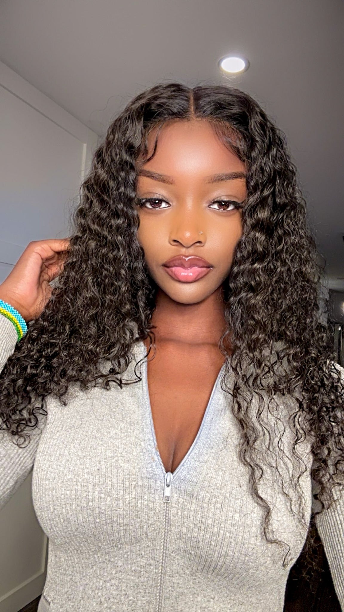A woman wearing a glueless, pre-bleached, tiny knots wig with a natural hairline and curly hair texture.