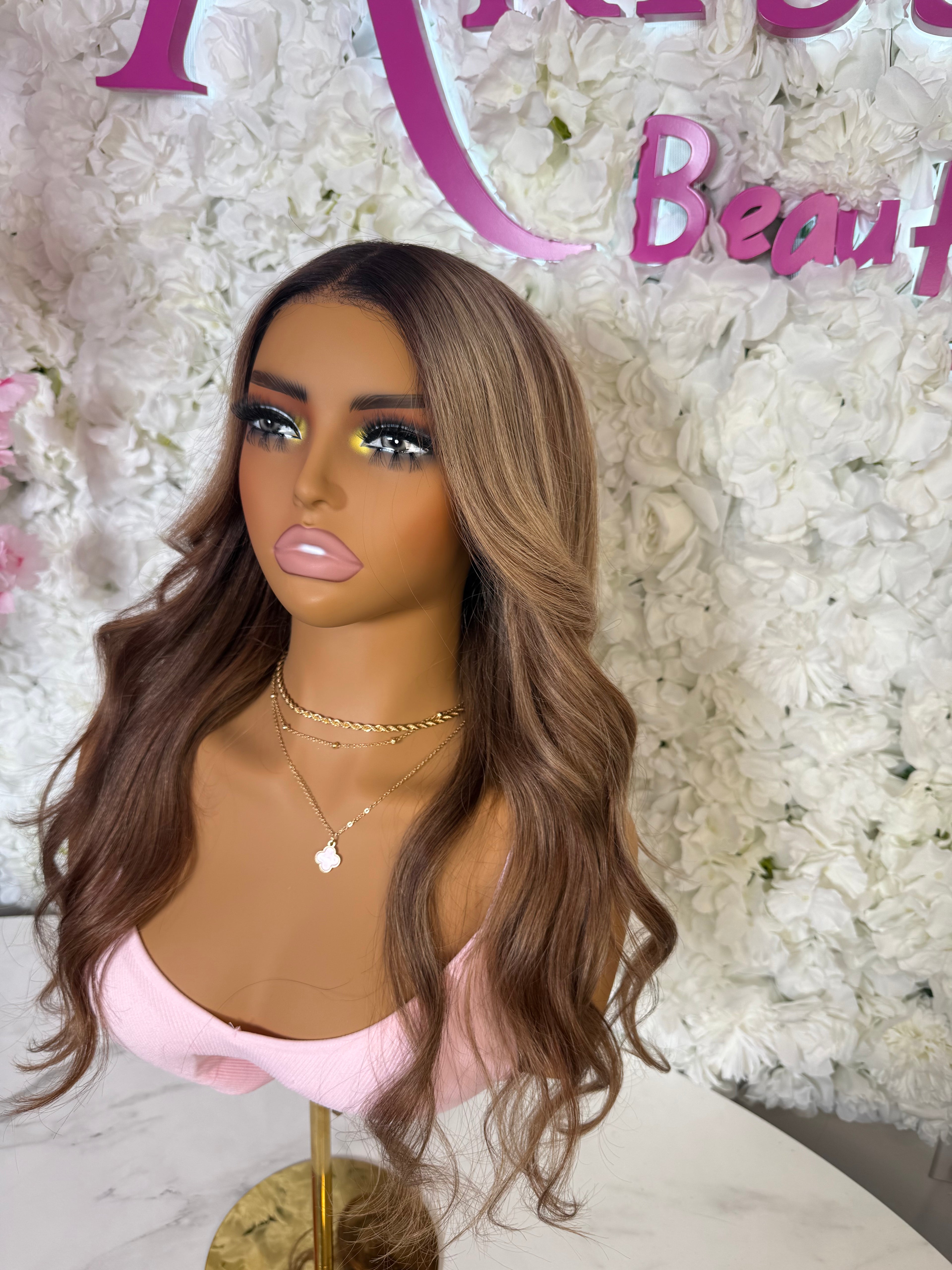 Mannequin head with a brown wig against a floral background with &