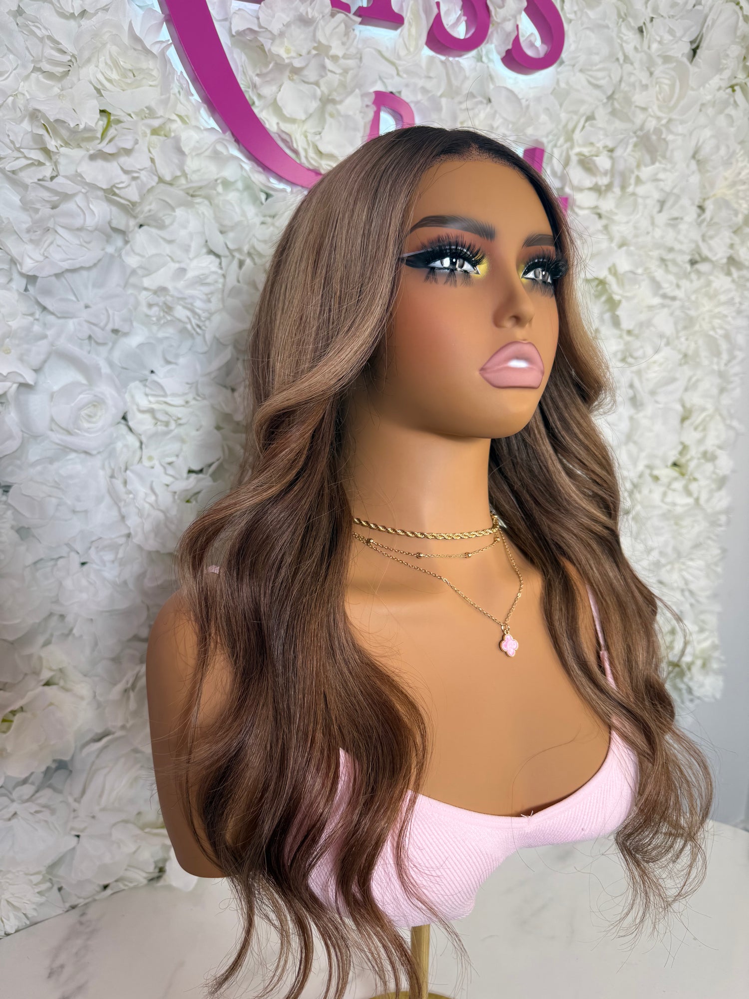 Mannequin head with long brown wig against a floral background