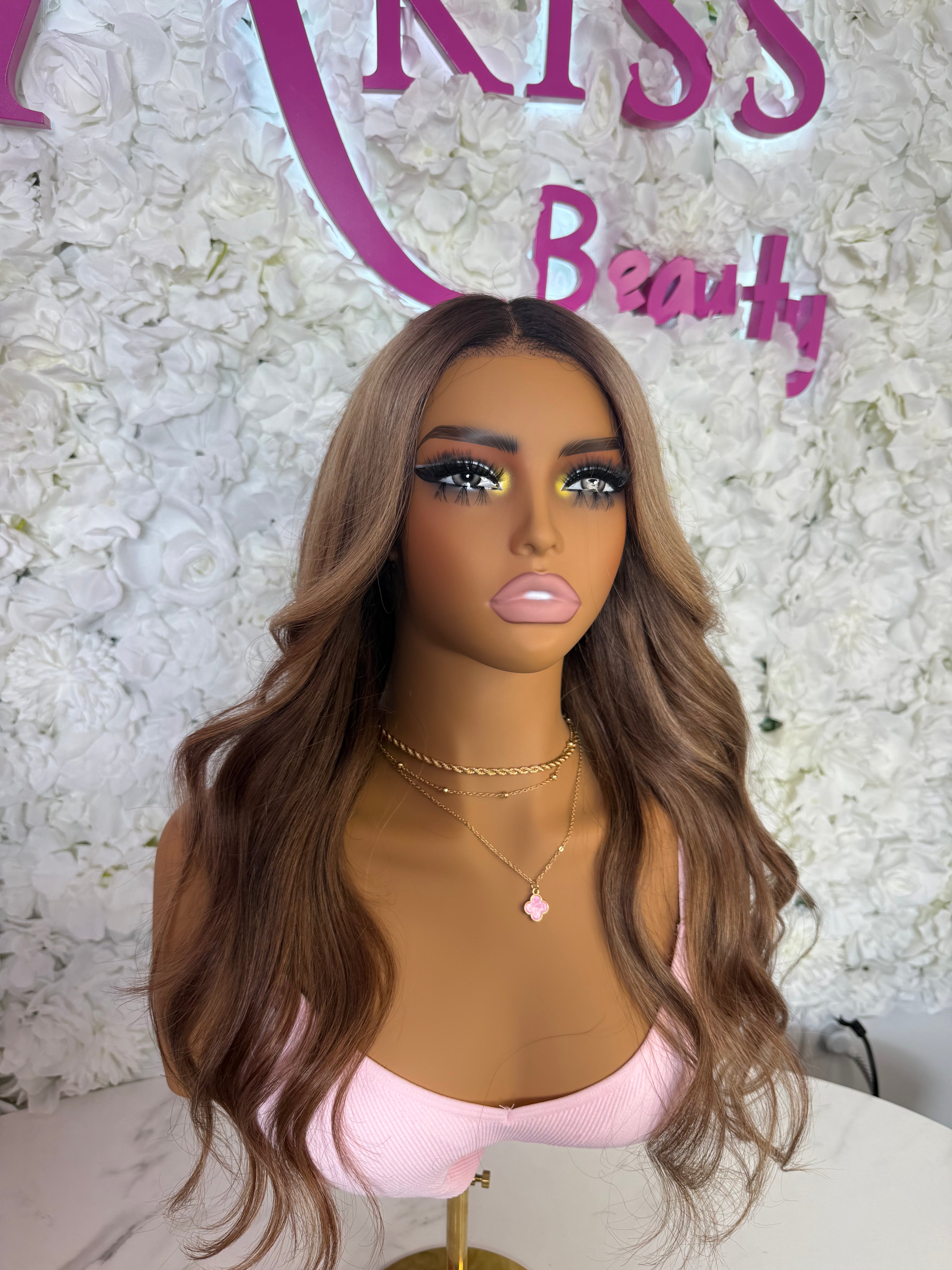 Mannequin head with long wavy brown hair against a floral background with &