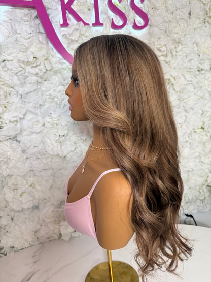Mannequin head with long brown wig against a floral wall with &