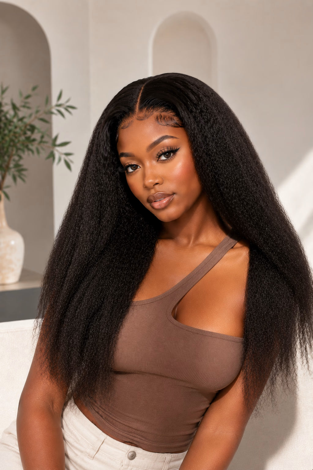 Woman with long, straight black hair wearing a brown top against a neutral background